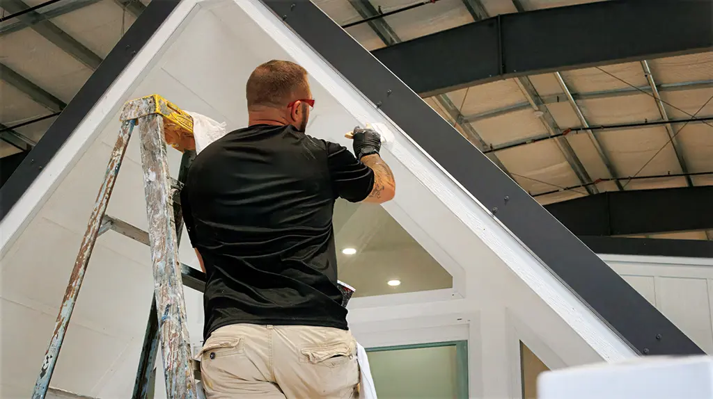 CallGOC technician painting an A-frame cottage gable