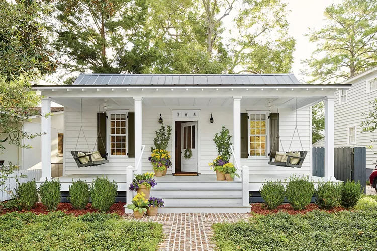 White cottage with a front porch and landscaping